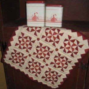 Little Red 4 This 17 1/2" square wall hanging or table topper features prairie points around the outside edge. Kit includes the pattern, fabrics for the top and binding, and the four red buttons.