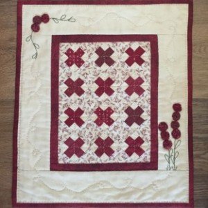 This Little Red is simply pieced, has a bit of embroidery, and little yo-yos that form the flowers. It is just 12" x 14". The kit includes all the fabrics needed for the top and binding, as well as the backing fabric and pattern.